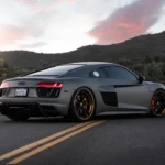 Black Audi vehicle driving on the road during a sunny day.