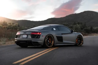 Black Audi vehicle driving on the road during a sunny day.