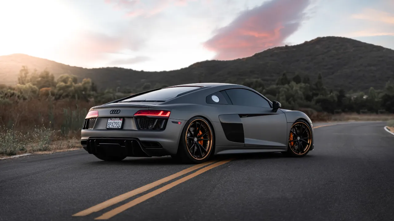 Black Audi vehicle driving on the road during a sunny day.
