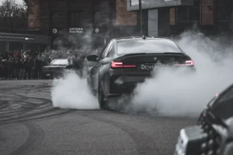 Black BMW sports car driving during daytime emphasizing pollution issues.