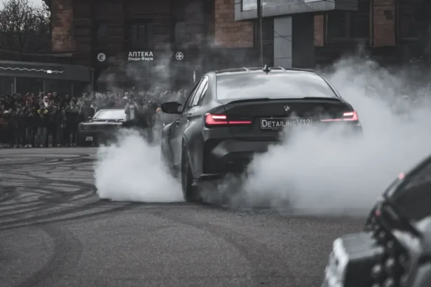 Black BMW sports car driving during daytime emphasizing pollution issues.