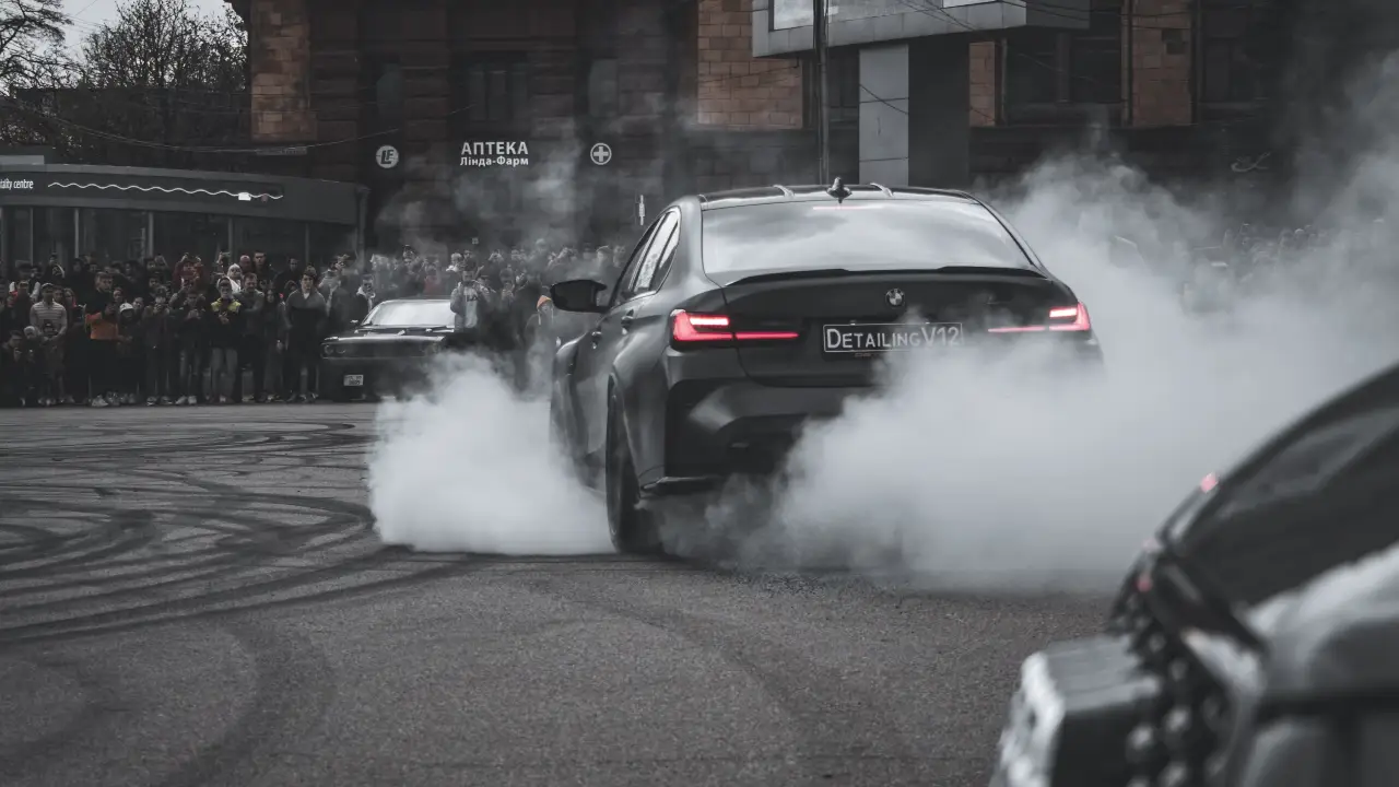 Black BMW sports car driving during daytime emphasizing pollution issues.