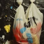 Plastic bag with colorful items on dark, debris-filled background emphasizing waste.