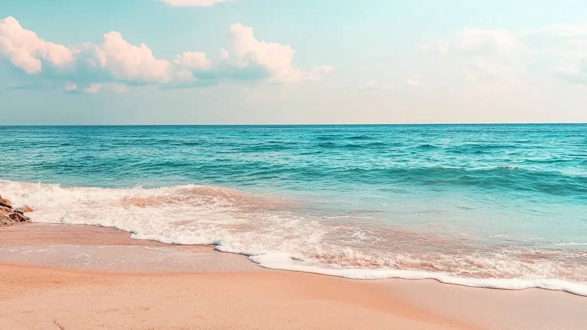Quiet beach with golden sand, turquoise waters, and a bright sky.