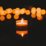 Calm candle with glow and bokeh lights creating a peaceful scene.