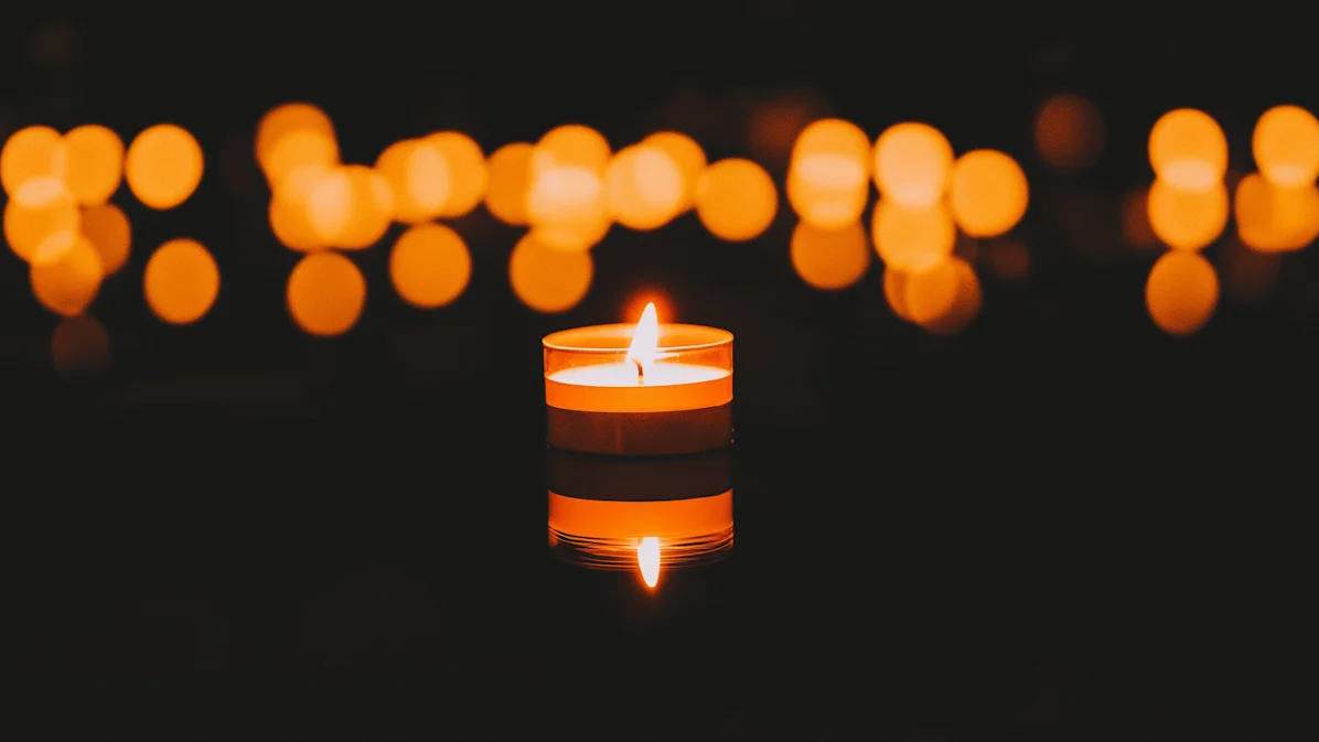 Calm candle with glow and bokeh lights creating a peaceful scene.