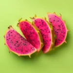 Colorful dragon fruit slices on green background showcasing their vivid flesh and seeds.