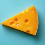 Swiss cheese slice with holes on turquoise background.