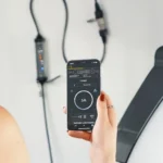 Woman in black dress charging EV while using her cellphone