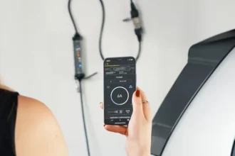 Woman in black dress charging EV while using her cellphone