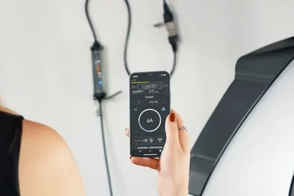 Woman in black dress charging EV while using her cellphone