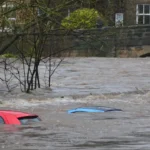 Car submerged in floodwaters during heavy flooding event.