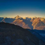 Swiss mountain range at sunset, rugged peaks with colorful sky.