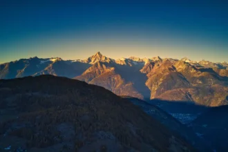 Swiss mountain range at sunset, rugged peaks with colorful sky.